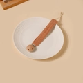 Détail d'une attache-tétine en gaze de coton caramel sur une assiette en céramique blanche - Style Mousseline Caramel (19)