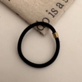 Detail of a high-elastic black hair tie with a decorative gold metal buckle on a neutral fabric - Black