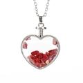Detalle de un colgante de corazón con piedras rojas y una cadena de metal plateado - Plata + Coral Rojo