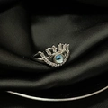 Macro shot of silver eye-shaped ring with blue zircon center on black silk fabric - Adjustable Open / Silver Blue Eye Style