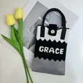 Close-up of tricolor knit tote bag with Grace lettering and elegant fashion props - Color Block Black-Grace