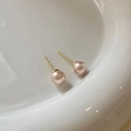 Close-up of pink pearl stud earrings with gold needles on a white ceramic plate - Pink (8mm)