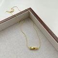 Close-up of golden geometric twisted pendant on thin snake chain over linen tray - 925 Silver / 18k Gold