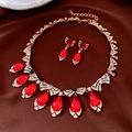 Dettaglio di parure vintage dorata con pietre a goccia rosse su raso marrone elegante - Collana-Rosso-Oro (Set da Due Pezzi)
