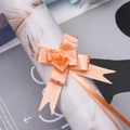 Macro view of orange pull bow ribbon with embossed floral patterns for gift wrapping - Orange Rose