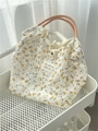 Détail d'un sac cabas floral en toile avec anses tissées sur un chariot blanc - Floral Jaune et Blanc
