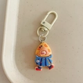 Close-up of cute cartoon girl keychain with yellow hair and blue dress in a beige tray - Cheese Girl