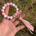 Close-up of pink leopard print beaded keychain bracelet with faux leather tassel - Pink