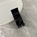 Minimalist black plastic hair clip for ponytail on a white ceramic plate background - Bright Black