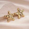 Close-up of gold starfish earrings with hammered texture on beige stone and silk - Starfish Style (Steel Pin) / Gold