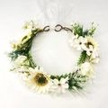 Detailansicht eines Sonnenblumen-Haarkranzes mit weißen Gänseblümchen und grünen Blättern - Weiße Gänseblümchen Sonnenblume Stil