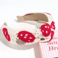 Close-up of a cream knitted headband featuring embroidered red and brown mushroom patterns - No Stem Strawberry Knotted
