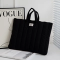 Close-up of black quilted laptop sleeve with vertical stitching and woven brand label - 11" / Black