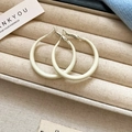 Close-up of cream white enamel hoop earrings on a beige linen jewelry display box - Cream White