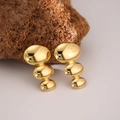 Detailed view of triple-tiered geometric gold earrings on textured brown mineral stone - EH136-Oval Module