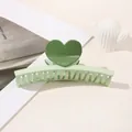 Close-up of a two-tone green heart hair claw clip on a minimalist white desk setting - Heart Straight / Light Green