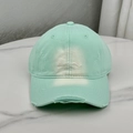 Close-up of mint green cotton baseball cap with embroidered letters and distressed details - Green