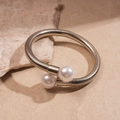 Detailed macro view of silver metallic spring collar with dual white pearl accents - Bracelet - Silver
