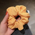 Handheld view of orange fabric scrunchie with white polka dot pattern for women hair - Ginger Yellow