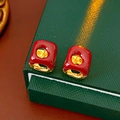 Detail of red enamel gold-tone square hoop earrings displayed on a green texture box - Ear Buckle / Red