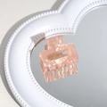 Detail view of champagne acetate hair claw on heart mirror with smooth pearly texture - Marble Pink