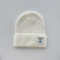 Close-up of white ribbed knit beanie featuring a stitched blue bear embroidery patch - One Size (Ages 3+) / White