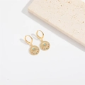 Detail of golden drop earrings featuring a round coin charm with a colorful evil eye motif - Evil Eye Round