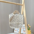 Waterproof baby bib in grey floral print with front pocket on a wooden hanger - Fun Floral 1