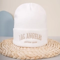 Close-up of the vintage LOS ANGELES gold embroidery on a white knitted beanie hat - One Size / White