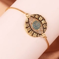 Detail of gold evil eye bracelet with colorful zircons on a soft beige fabric background - Classic Evil Eye Style (Style 6)