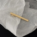 Dettaglio ravvicinato di un fermaglio per capelli rettangolare in metallo dorato lucido - Stile Rettangolare Sottile Oro