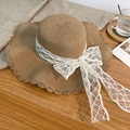 Brown woven straw beach hat featuring large wavy brim and white lace bow decoration - Khaki Lace Decor