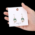 Christmas bell earrings with white finish, green bow and pearl detail held in hand - White Bell with Pearl