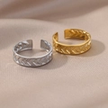 Dettaglio di anelli regolabili oro e argento con texture a V su tessuto beige - Chevron a V Geometrico / Oro