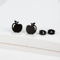 Detailed close-up of matte black stainless steel apple-shaped stud earrings on white pedestal - Black Apple