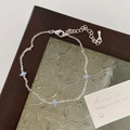 Detailed shot of silver bracelet featuring light blue flower charms on a vintage glass tray - Clover Bracelet / Silver Blue