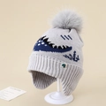 Detail of grey knitted kids hat with jacquard dinosaur pattern and large faux fur pompom - 3-8 Years / Gray
