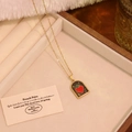 Detailed close-up of a vintage arch pendant with a red enamel heart on a gold chain - Black