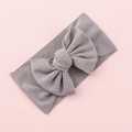 Detail of grey ribbed knit baby headband with large elastic bow on pink background - Gray