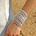 Pulseras de cuentas blancas y plateadas en la muñeca con un fondo de playa soleada - Juego de 20 Piezas Blanco