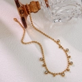 Detail of gold beaded necklace with transparent zircon pendants on a white background - Gold White Zirconia