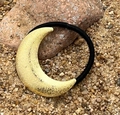 Detailopname van gouden glitterende maan haarelastiek op zand en natuursteen - Maan