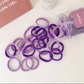 Nahaufnahme lila elastischer Haargummis in einer Flasche auf minimalistischem Tisch - 50 Stück/Rohr / Lila Serie