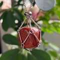 Macro shot of red goldstone pendant in a silver woven wire mesh necklace cage - Synthetic Goldstone