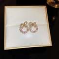Dettaglio macro di orecchini a fiocco dorati con zircone rosa e perle bianche - Perno in Argento S925 / Fiocco di strass rosa