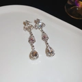 Primer plano de pendientes plateados con cristales rosas y flores de strass en plato blanco - Estilo de Pendientes de Gota (Aguja de Plata-Plata-Rosa)