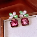 Makro-Detail von Vintage-Ohrringen mit roten Edelsteinen und bunten Kristallen auf Stoff - Rosa Grün Lila (Silbernadel Silber Stil)