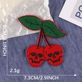 Skull cherry embroidered patch with green leaves and dimensions on denim background - 8cmx7.3cm