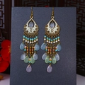 Detail of bohemian drop earrings with colorful beads and fringes on a display board - Iridescent White