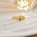 Detailed macro of a golden crown ring with a green gemstone on a ceramic tray - Green Stone Crown Style (JZ0135B)